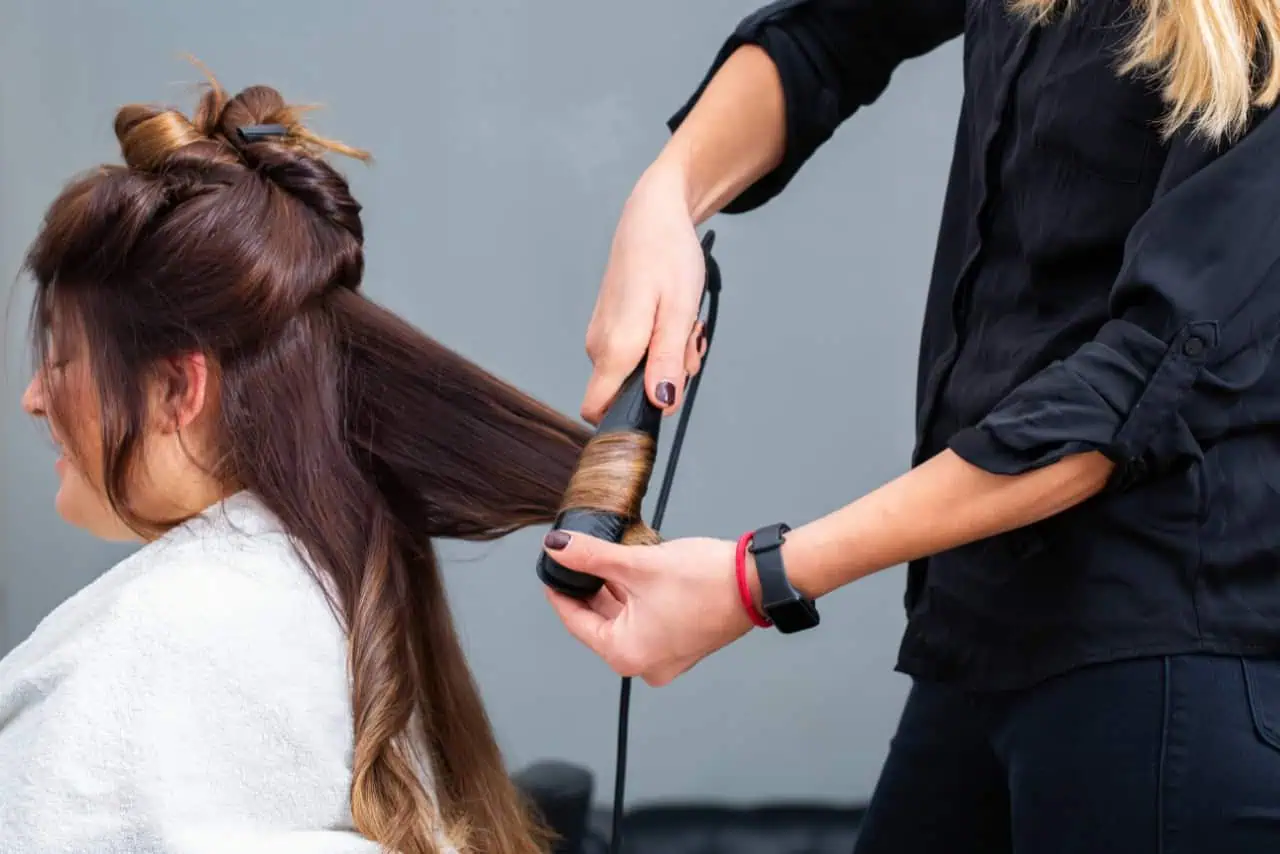 Woman having her hair styled with a curling iron.